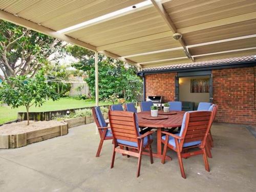 a wooden table and chairs on a patio at Benjos by Experience Jervis Bay in Vincentia