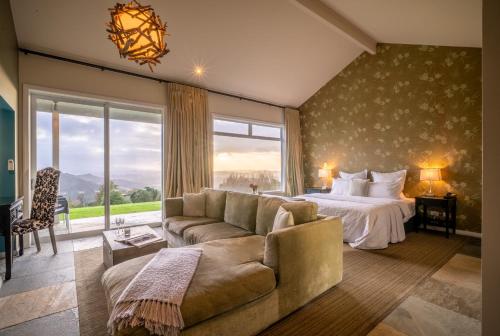 a bedroom with a bed and a couch and a large window at Woodhouse Mountain Lodge in Warkworth