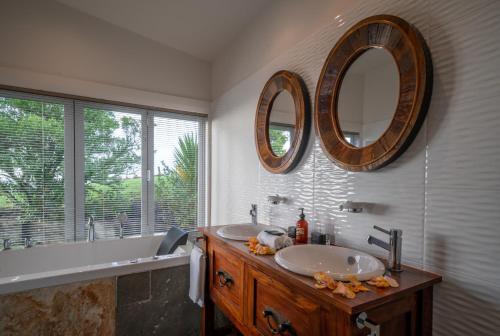a bathroom with two sinks and two mirrors on the wall at Woodhouse Mountain Lodge in Warkworth