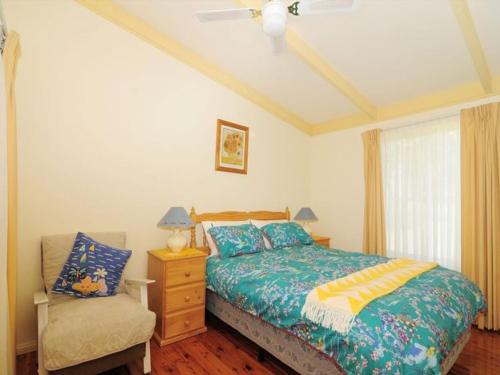 a bedroom with a bed and a chair and a window at Seaview by Experience Jervis Bay in Vincentia