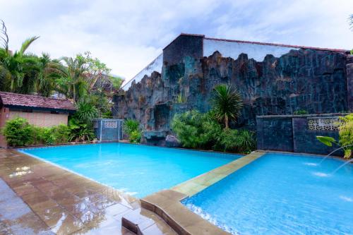 basen przed budynkiem ze ścianą skalną w obiekcie Hotel Mahkota Plengkung by ecommerceloka w mieście Banyuwangi