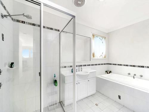 a white bathroom with a shower and a tub and a sink at The Porthole of Huskisson by Experience Jervis Bay in Huskisson