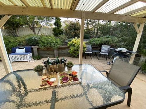 a patio with a glass table with food on it at The Porthole of Huskisson by Experience Jervis Bay in Huskisson