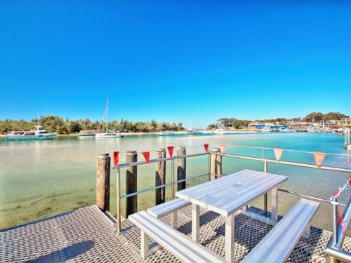a picnic table on a dock next to the water at The Porthole of Huskisson by Experience Jervis Bay in Huskisson