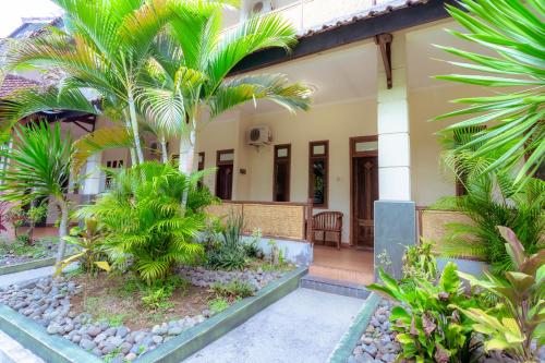 a house with palm trees in front of it at Hotel Mahkota Plengkung by ecommerceloka in Banyuwangi