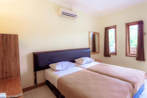 a bedroom with two beds and two windows at Hotel Mahkota Plengkung by ecommerceloka in Banyuwangi