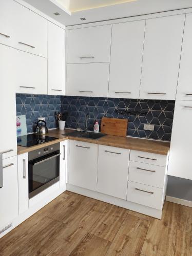 a kitchen with white cabinets and a wooden floor at Apartament Gdynia Oksywie z Tarasem , darmowy parking in Gdynia