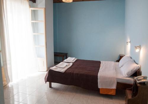 a bedroom with a bed and a blue wall at Apraos Bay Hotel In Kalamaki Beach in Apraos