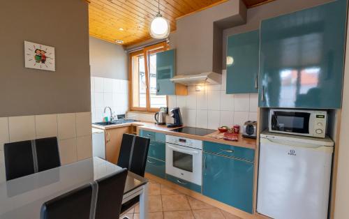 La cuisine est équipée de placards bleus et d'un réfrigérateur blanc. dans l'établissement Le Schwendala - Quartier Petite Venise, à Colmar