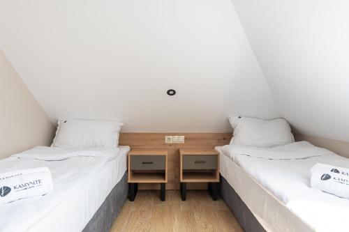 two twin beds in a room with white walls at Хотел Камъните in Burgas