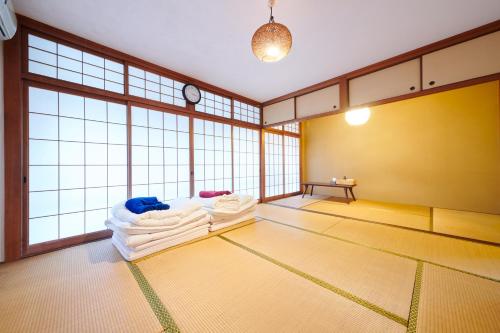 an empty room with towels on a floor with windows at Hostel Coliberty in Tokushima