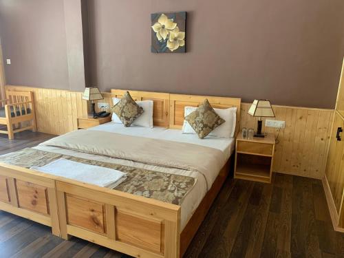 a bedroom with a large wooden bed with two tables at Adu's Eternal Comfort in Leh