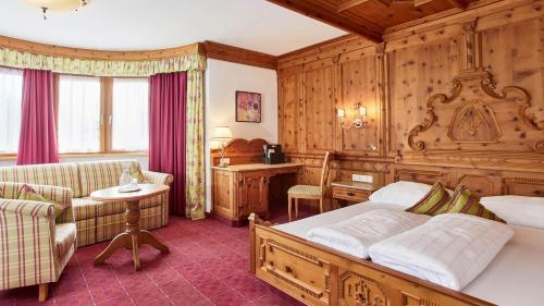 a bedroom with a bed and a couch and a table at All In Resort Schwarzbrunn - 4 Sterne Superior in Stans