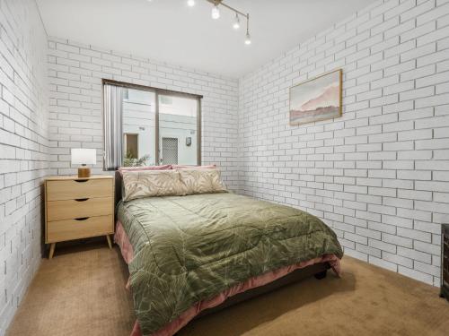 a bedroom with a bed and a brick wall at Ammos by Experience Jervis Bay in Vincentia