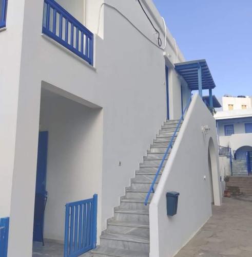a white building with blue doors and stairs at Xristiana's House in Tinos Town