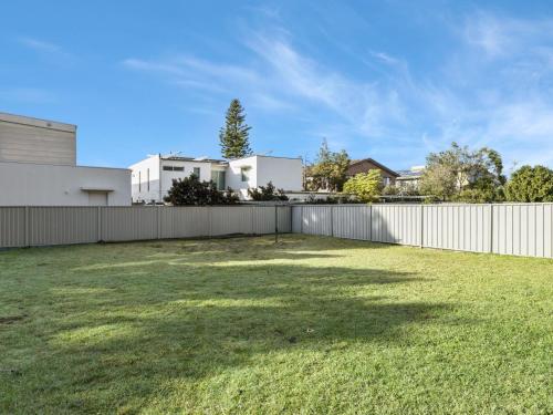 a large yard with a fence and a house at Ammos by Experience Jervis Bay in Vincentia