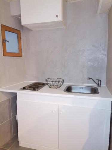 une cuisine blanche avec un évier et un comptoir dans l'établissement Studio Montpellier écusson, à Montpellier
