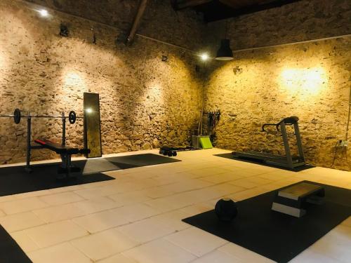 um ginásio com pesos e equipamento de exercício numa parede de tijolos em Le Voyageur - Chambres d'Hôtes em Olonzac