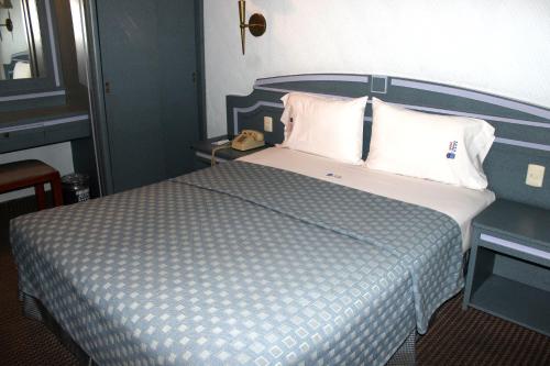 a bedroom with a large bed with white pillows at Hotel Monaco in Mexico City