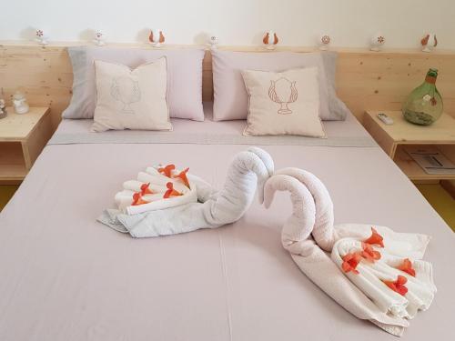 Dos cisnes hechos de toallas en una cama en Appartamento Verde mare, en Torre Pali