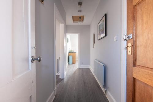 a hallway with white walls and a wooden door at Dryburgh Apartments No2 in Inverness