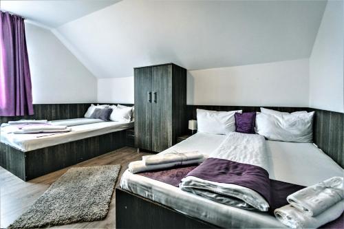two beds in a room with purple curtains at Pensiunea Adriana Straja in Straja