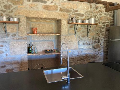 a kitchen with a sink and a stone wall at Casa da Belavista in Vilar de Nantes