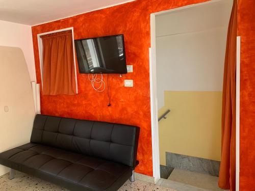 a room with a couch and a tv on a wall at Le casette nel cortile in Sciacca