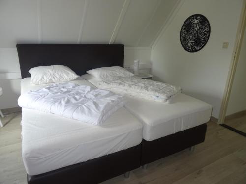 two beds in a bedroom with white sheets and pillows at Kustverhuur, Park Schoneveld, Stern 234 met eigen elektrische laadpaal in Breskens