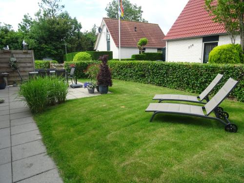 a bench sitting in the grass in a yard at Kustverhuur, Park Schoneveld, Stern 234 met eigen elektrische laadpaal in Breskens