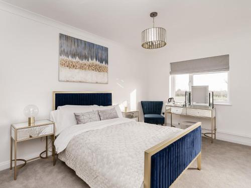 Schlafzimmer mit einem blauen und weißen Bett und einem Schreibtisch in der Unterkunft Pike and Eel Hotel and Marina in Needingworth