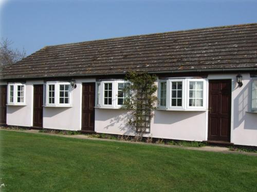 a white house with a brown roof and green grass at Pike and Eel Hotel and Marina in Needingworth