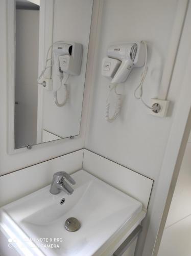 La salle de bains est pourvue d'un lavabo, d'un miroir et d'un sèche-cheveux. dans l'établissement MOBIL HOME 6 personnes TOUT CONFORT, à Saint-Cyprien