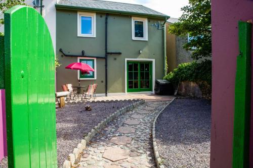a house with a green door and a table with a pink umbrella at Dingle Town Holiday Home by Trident Holiday Homes in Dingle