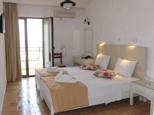 a bedroom with a large white bed with two pillows at Dimitra Hotel in Hersonissos