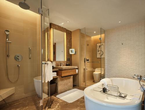 a bathroom with a tub and a toilet and a sink at HUALUXE Ningbo Harbor City, an IHG Hotel in Ningbo