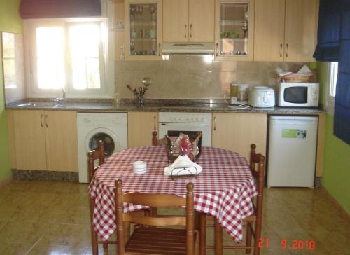 a kitchen with a table with a red and white table cloth at Apartamentos Turísticos San Breixo in Carballo