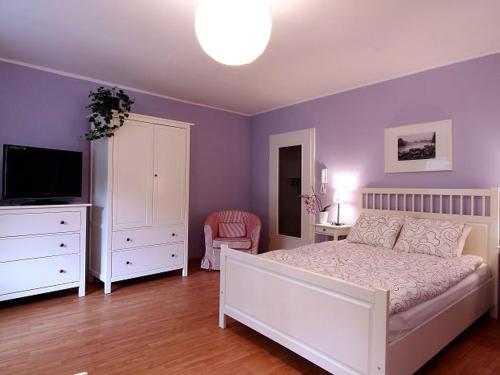 a bedroom with a white bed and a television at Ferienwohnungen Brigitte in der Altstadt in Bad Reichenhall