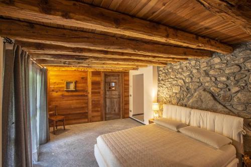 - une chambre avec un lit et un mur en pierre dans l'établissement L'Atelier du Temps - Baita Grandes Jorasses, à Montita