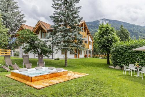 a backyard with a table and chairs and a house at Chalet Mountain Plaza - Apt Greenvalley in Pinzolo
