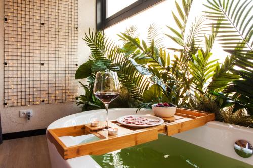 a bath tub with a glass of wine and a table at Hospedium H Cabo Sport in Finisterre