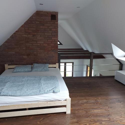 a bedroom with a bed and a brick wall at Szewnia Dolna in Szewnia