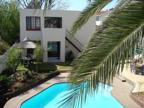 a palm tree in front of a house with a swimming pool at Louhallas Accommodation in Edenvale