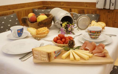 a table with a cutting board with cheese and fruit at Mas dei Masi in Cavalese