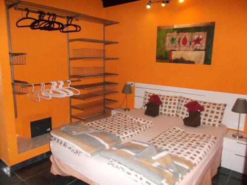 ein Schlafzimmer mit einem Bett mit einer orangefarbenen Wand in der Unterkunft Modern holiday home with balcony with sea and mountain views no Teide-view in Icod de los Vinos