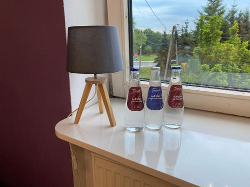 Willa nad Sołą guest house في أوشفيتز: ثلاث زجاجات جالسة على حافة النافذة بجوار مصباح