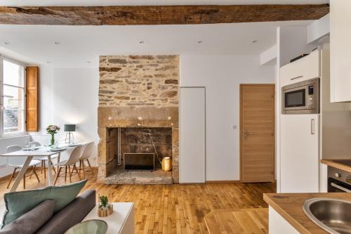 uma cozinha e sala de estar com lareira de pedra em Le Cerf Volant - une pépite à l'Intramuros em Saint Malo