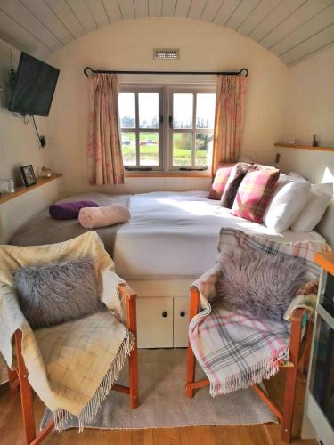 a bedroom with a large bed and two chairs at Fair Farm Hideaway in Waltham on the Wolds