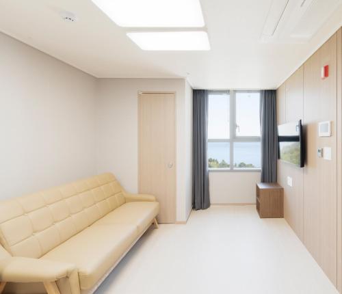 a living room with a couch and a television at Donghae Oceancity Residence Hotel in Donghae