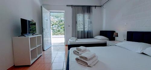 1 dormitorio con 2 camas, TV y balcón en On The Rocks, en Qeparo
